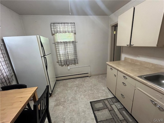 kitchen featuring white refrigerator, light tile patterned floors, baseboard heating, and sink