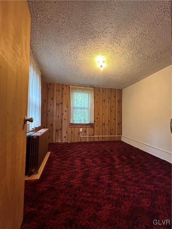 carpeted spare room with radiator and a textured ceiling