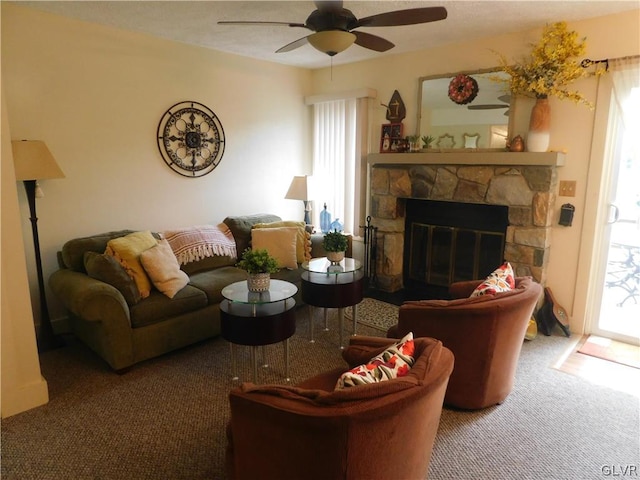 living room featuring ceiling fan, a stone fireplace, and carpet floors