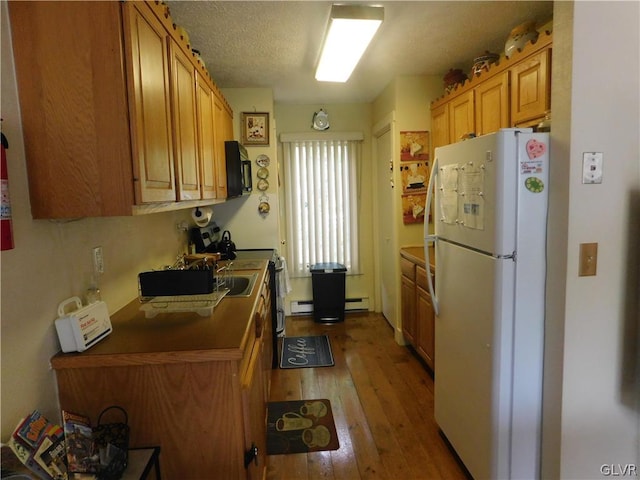 kitchen featuring a baseboard heating unit, light wood-type flooring, a textured ceiling, and white fridge