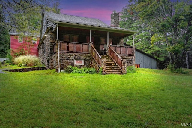 back house at dusk featuring a lawn