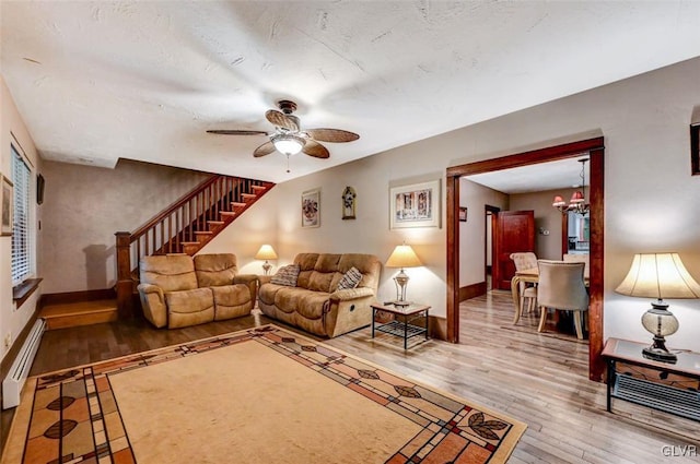 living room with ceiling fan with notable chandelier, a baseboard radiator, and hardwood / wood-style flooring