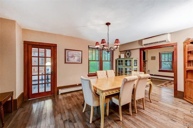 dining space with baseboard heating, hardwood / wood-style flooring, a wall mounted AC, and a chandelier