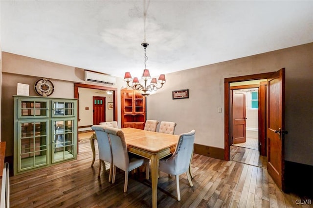 dining room featuring an AC wall unit, wood-type flooring, and an inviting chandelier