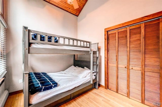 bedroom featuring high vaulted ceiling, light wood-type flooring, a closet, and wood ceiling