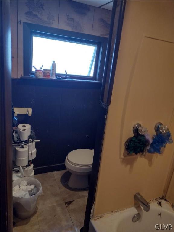 bathroom featuring shower / tub combination, tile patterned floors, and toilet