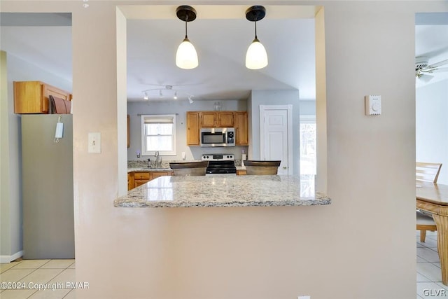 kitchen featuring ceiling fan, pendant lighting, sink, kitchen peninsula, and appliances with stainless steel finishes