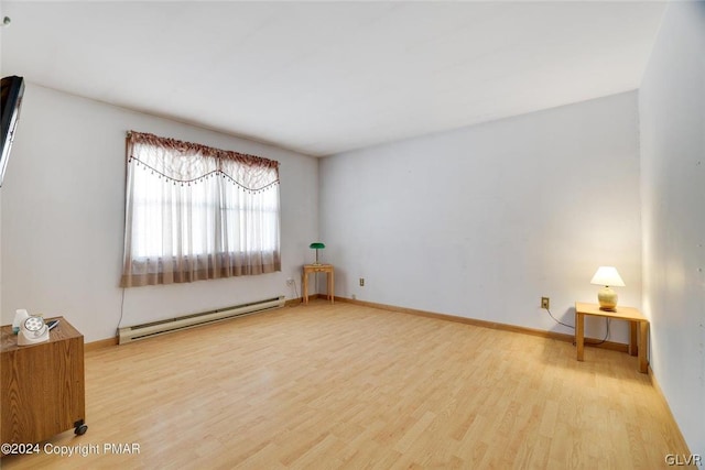 spare room featuring baseboard heating and light wood-type flooring