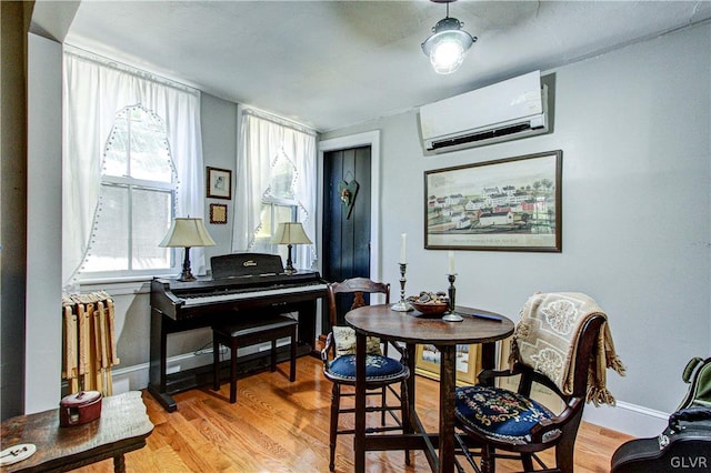 dining space with a wall unit AC and light hardwood / wood-style flooring