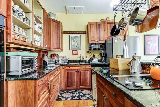 kitchen featuring dark stone counters, light hardwood / wood-style floors, black appliances, and sink