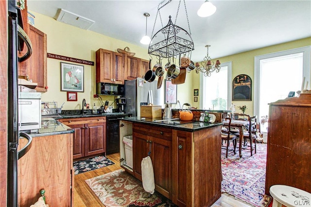 kitchen with a kitchen island, light wood-type flooring, stainless steel fridge, and decorative light fixtures