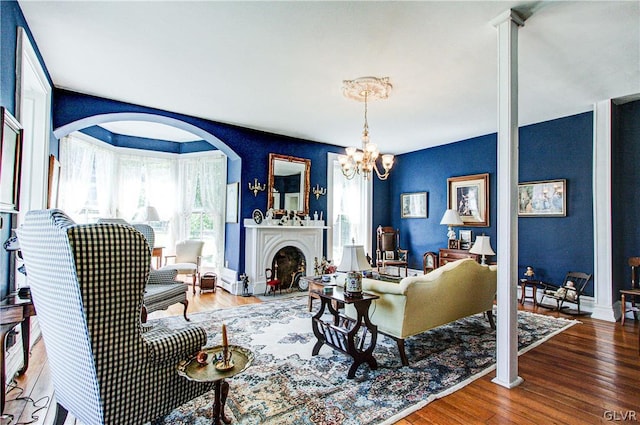 living room with hardwood / wood-style flooring, ornate columns, and an inviting chandelier