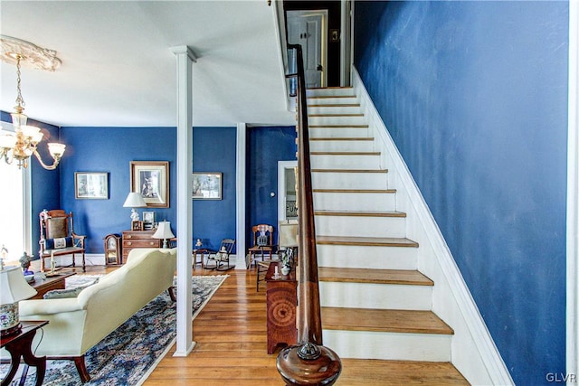 staircase with an inviting chandelier and wood-type flooring