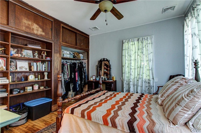 bedroom featuring ornamental molding, multiple windows, wood-type flooring, and ceiling fan