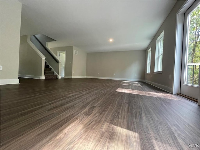 unfurnished living room with dark wood-type flooring and a wealth of natural light