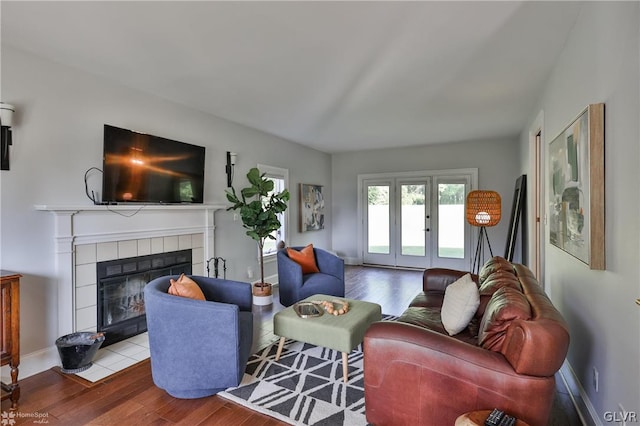 living room with wood-type flooring, a tile fireplace, and french doors