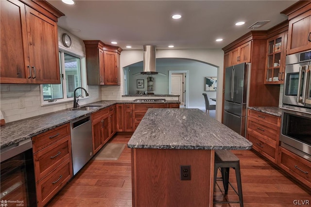 kitchen featuring tasteful backsplash, dark hardwood / wood-style flooring, a kitchen island, stainless steel appliances, and wall chimney exhaust hood