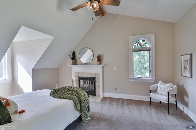 bedroom featuring multiple windows, light carpet, ceiling fan, and a tiled fireplace