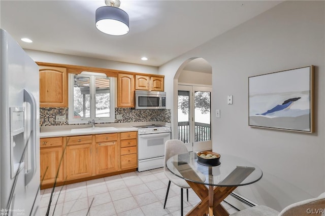 kitchen with sink, tasteful backsplash, light tile patterned floors, and white appliances