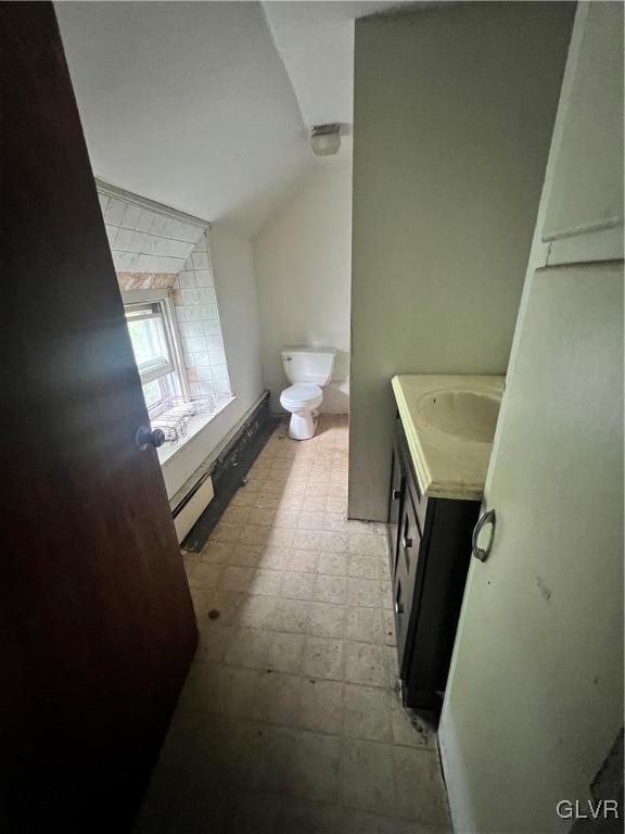 bathroom featuring lofted ceiling, vanity, toilet, and a baseboard heating unit