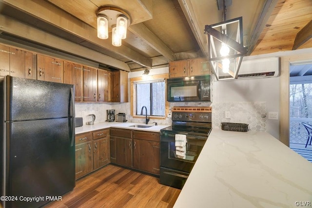 kitchen with sink, tasteful backsplash, an AC wall unit, beam ceiling, and black appliances