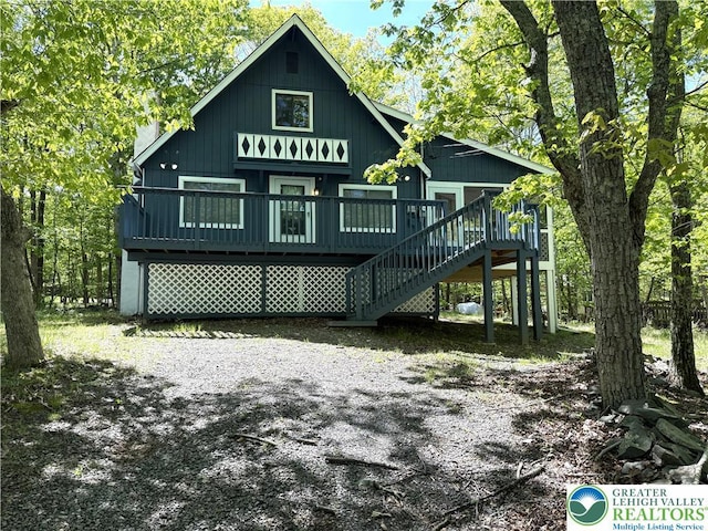 back of property with a deck and stairs