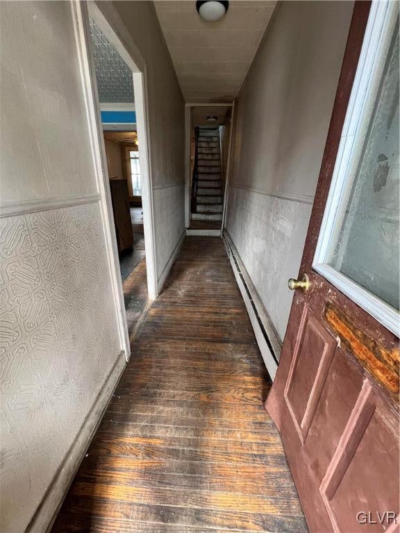 hall with a baseboard heating unit and dark wood-type flooring