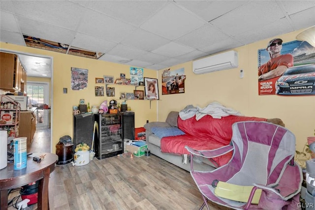 bedroom with hardwood / wood-style flooring, a drop ceiling, and a wall unit AC