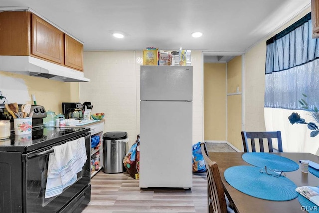 kitchen with light hardwood / wood-style flooring, black / electric stove, and white refrigerator