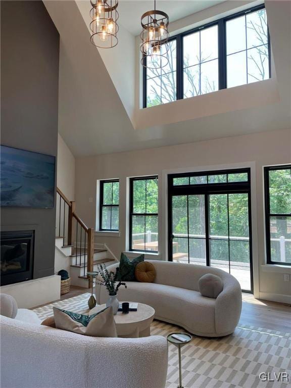 living room with a healthy amount of sunlight, a high ceiling, wood-type flooring, and a chandelier