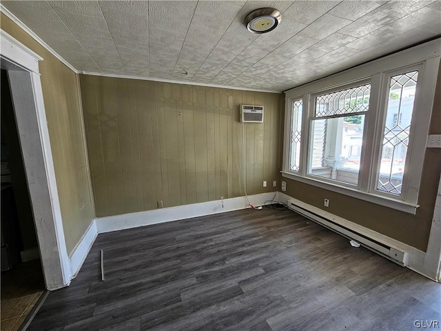 spare room featuring dark wood-type flooring, baseboard heating, a wall mounted air conditioner, and wooden walls