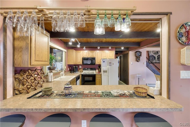 kitchen featuring white appliances, wooden ceiling, beamed ceiling, sink, and kitchen peninsula