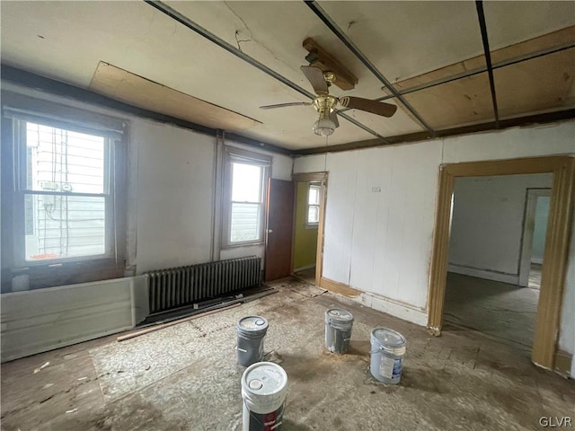 spare room featuring radiator, ceiling fan, and plenty of natural light