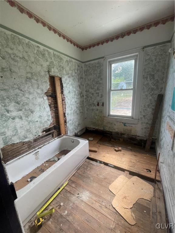 bathroom with wood-type flooring and a tub to relax in