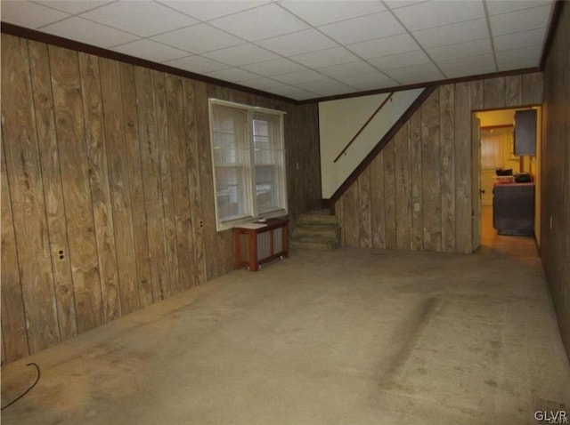 interior space with radiator, wood walls, carpet floors, and a paneled ceiling