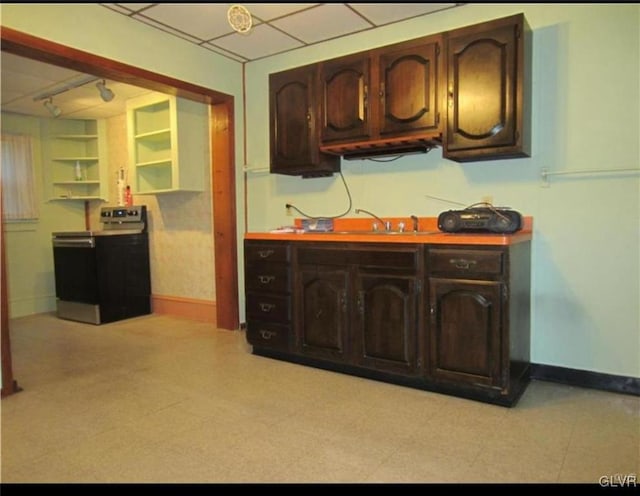 kitchen featuring electric stove, dark brown cabinetry, and sink