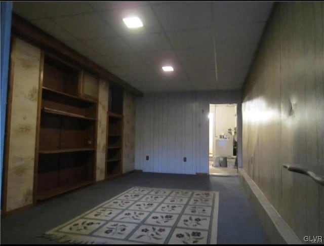 spare room with wooden walls, built in features, and a paneled ceiling