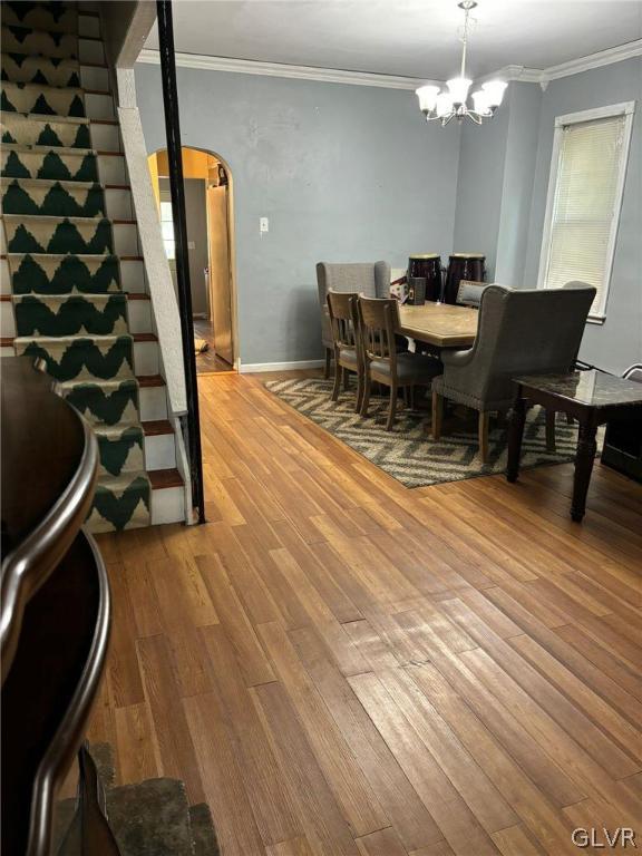 dining space featuring an inviting chandelier, ornamental molding, and hardwood / wood-style floors