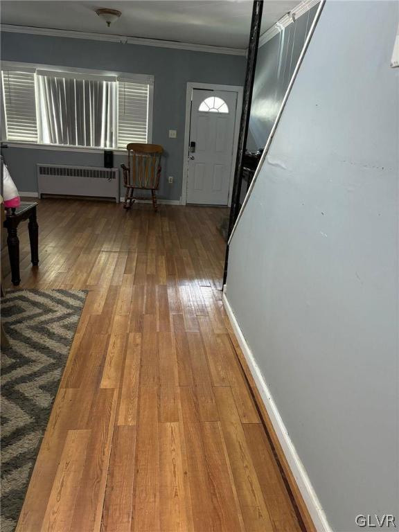 entryway featuring radiator heating unit, wood-type flooring, and ornamental molding