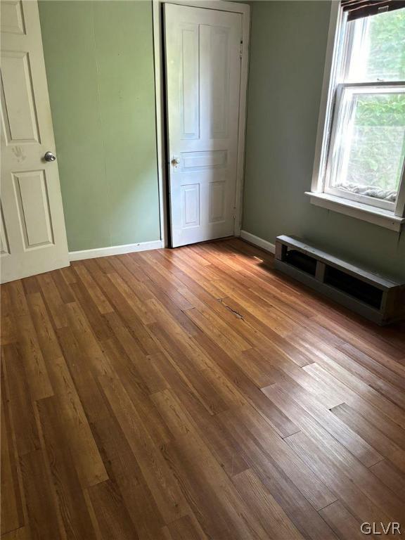 unfurnished bedroom featuring a baseboard radiator and hardwood / wood-style floors