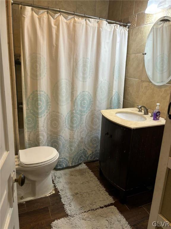 bathroom with vanity, toilet, and tile walls