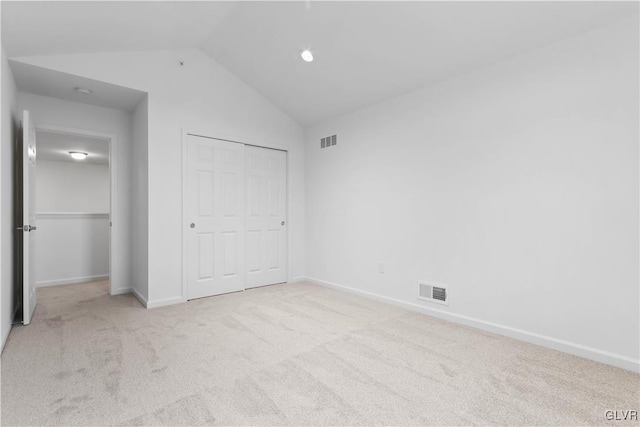 unfurnished bedroom featuring light colored carpet, a closet, and lofted ceiling