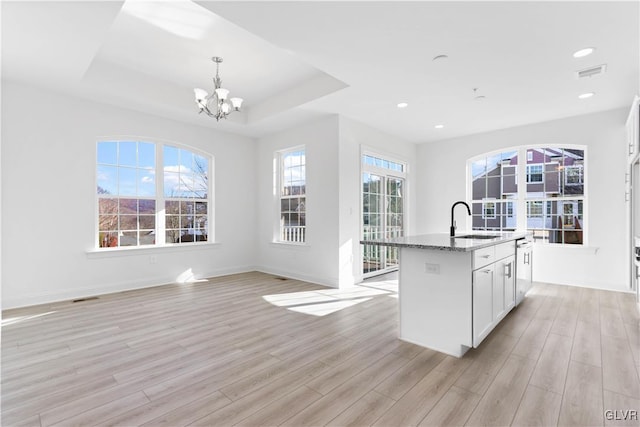 kitchen with a kitchen island with sink, a healthy amount of sunlight, and light wood-type flooring