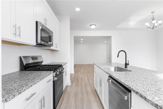 kitchen with white cabinetry, sink, stainless steel appliances, light stone counters, and light wood-type flooring