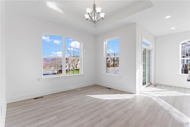 unfurnished dining area featuring an inviting chandelier, a healthy amount of sunlight, and light wood-type flooring