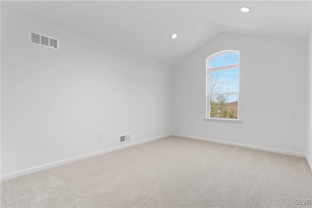 carpeted empty room featuring lofted ceiling