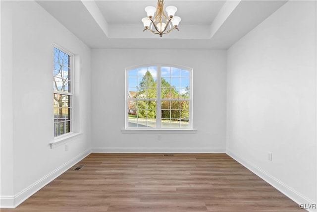 unfurnished dining area featuring plenty of natural light, hardwood / wood-style floors, and an inviting chandelier