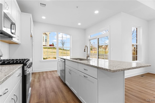 kitchen with sink, white cabinets, wood-type flooring, and appliances with stainless steel finishes