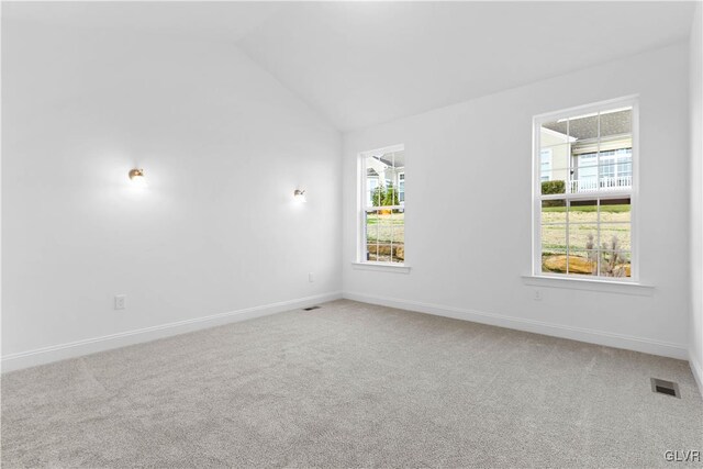 carpeted spare room featuring vaulted ceiling