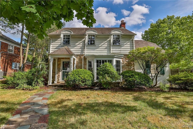 view of front of house with cooling unit and a front lawn